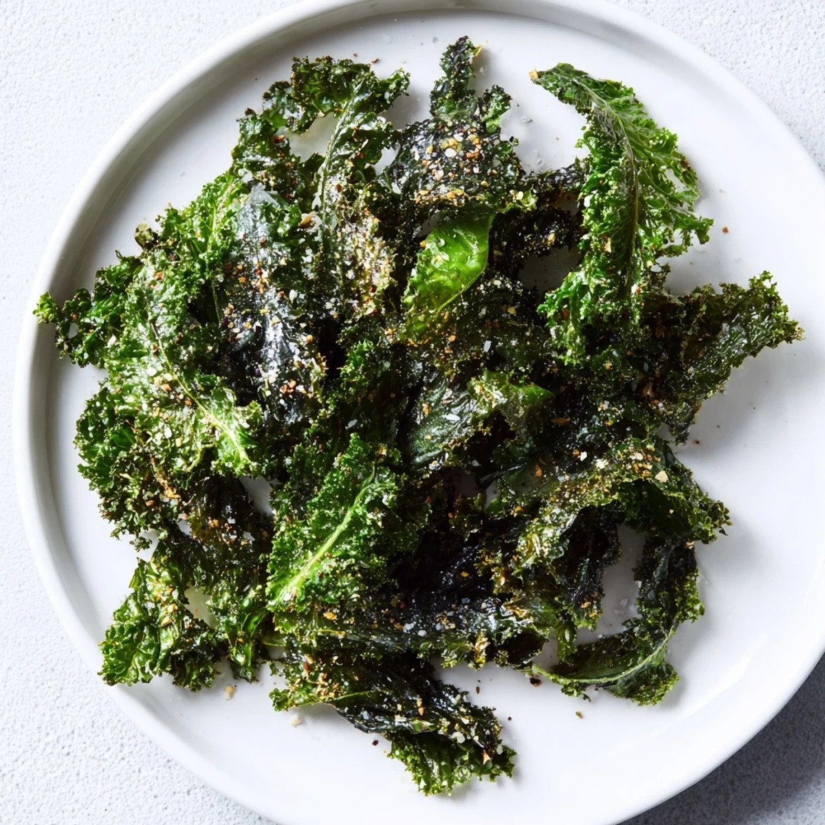 A close-up of vibrant green baked kale chips, perfectly seasoned and ready to eat.
