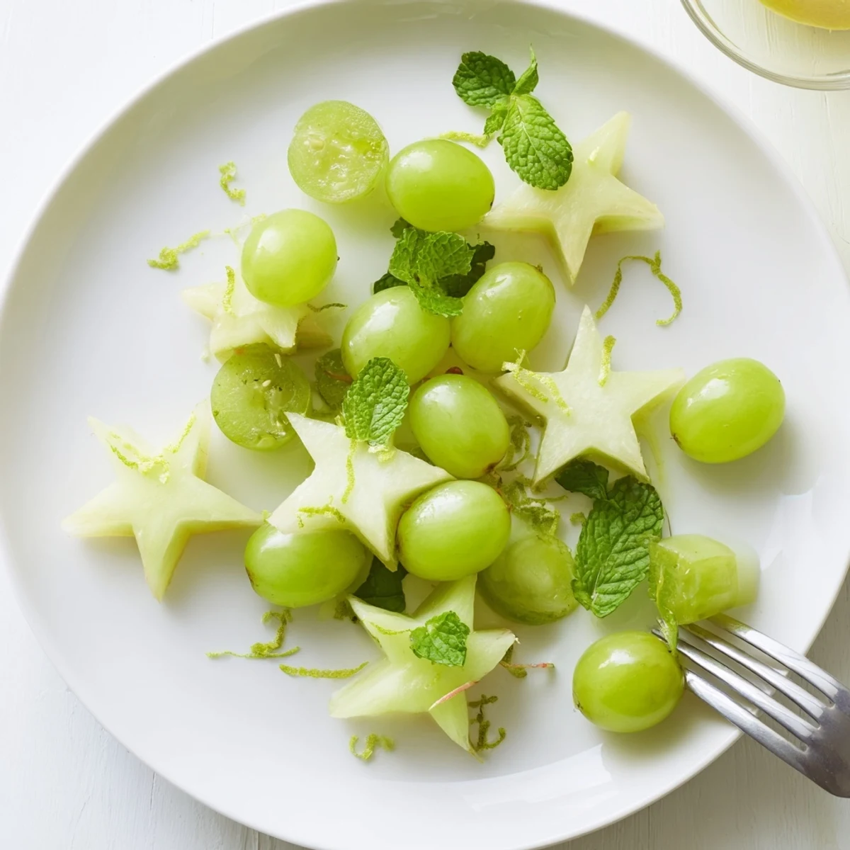 Freshly sliced starfruit and halved grapes, a colorful Brunch Fruit dish, ready to eat alongside waffles.