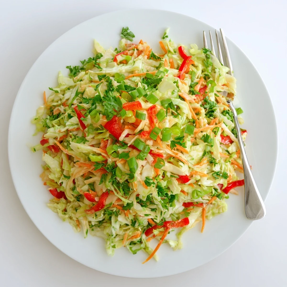 Healthy vegan Sauerkraut Slaw served chilled, topped with crisp red bell pepper slices, green onions, and fresh parsley garnish.  