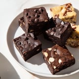 Warm, freshly baked brownie and blondie squares, arranged together on a serving plate.
