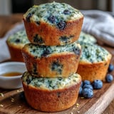 A single Vegan Blueberry Lemon Protein Muffin broken open to reveal a fluffy interior and plump blueberries.