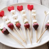View a festive Cupid's Arrow Candy Tray, complete with chocolate-covered strawberries and playful candy arrows.