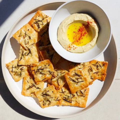 Golden Holiday Crackers are shown with creamy hummus, an easy and festive appetizer.