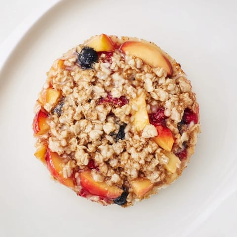 View of a home-baked Fruit Crisp featuring sweet frozen fruit, served warm with a scoop of vanilla.