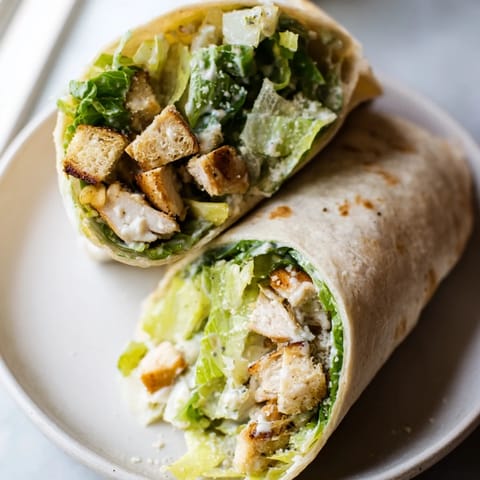 Freshly assembled Chicken Caesar Wraps, bursting with crisp lettuce and crunchy croutons.