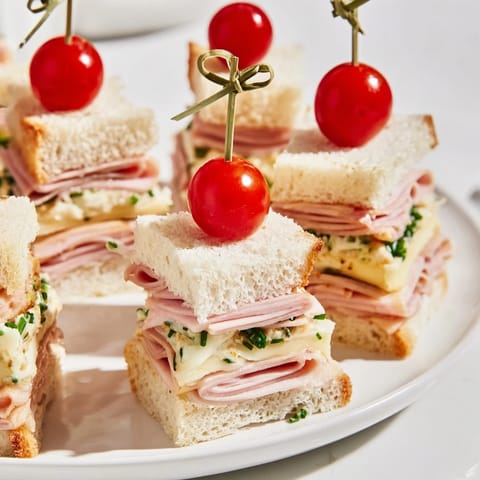 Homemade Mini Sandwiches: Ham and Cheese Christmas Tree towers, ready to eat with a sprig of fresh herbs.