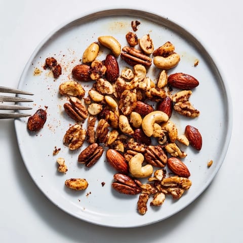 Spiced Nuts Mix roasted to perfection on a parchment-lined baking sheet, emitting a warm, smoky aroma.  