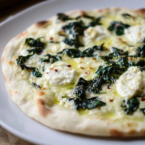 Freshly baked Spinach Ricotta Pizza slice on a wooden board, paired with salad and white wine.