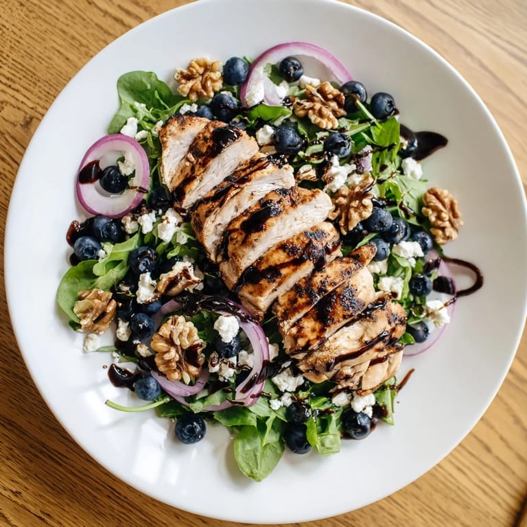 This flavorful Blueberry Goat Cheese Chicken Salad shows sliced chicken with crumbled goat cheese and a balsamic drizzle.