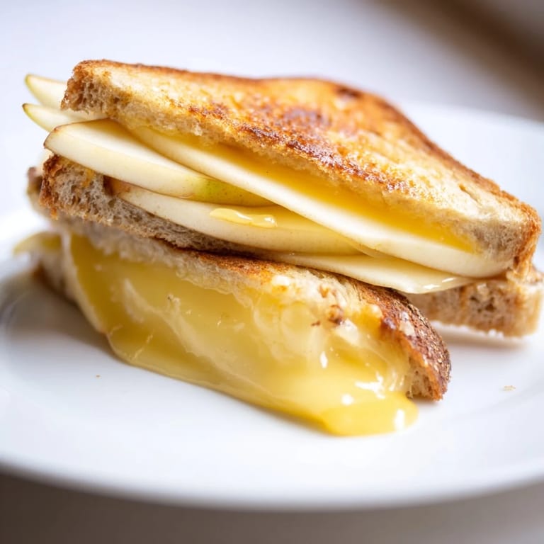 A gourmet Smoked Gouda & Apple Grilled Cheese sandwich, oozing creamy cheese and buttery, toasted bread.  